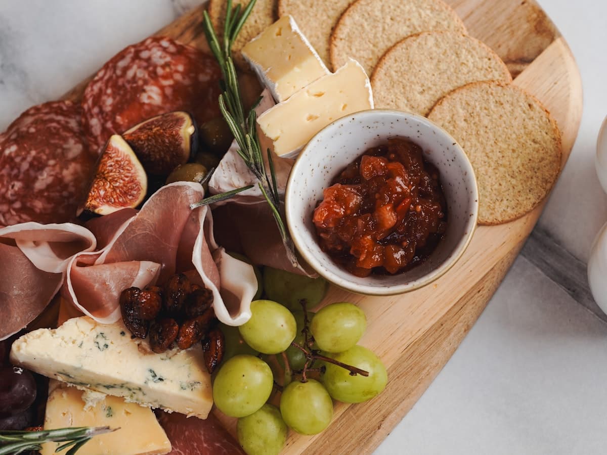 A charcuterie board with cured meats, cheeses, grapes and crackers