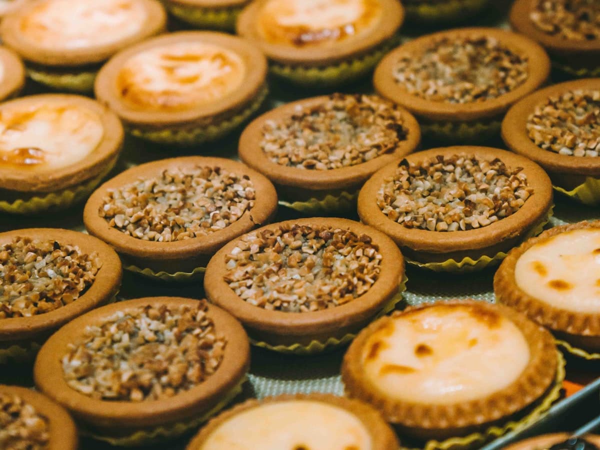 A tray of mini tarts topped with cream and chopped pistachio